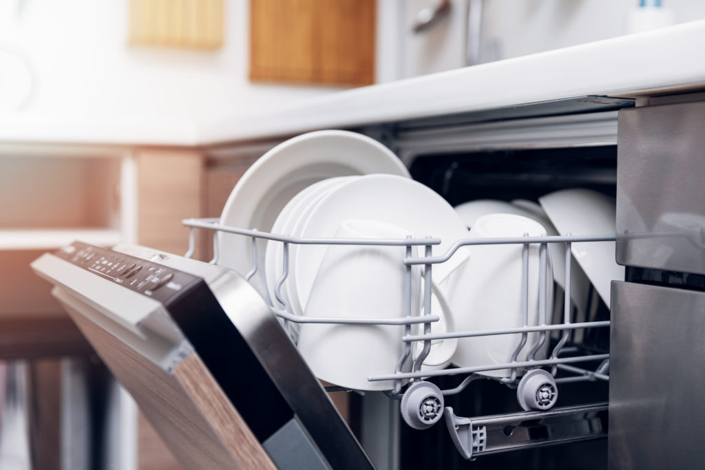 open dishwasher with clean dishes at home kitchen

